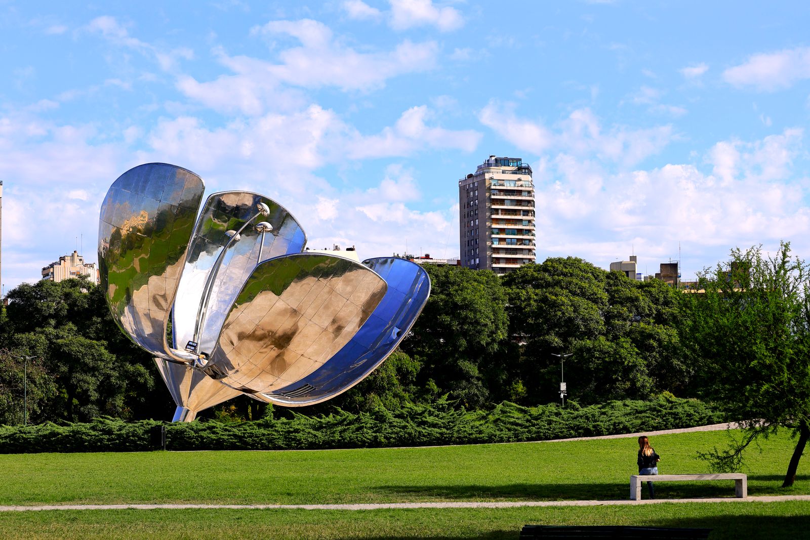 Floralis Generica sculpture in a Buenos Aires park with buildings in the background.