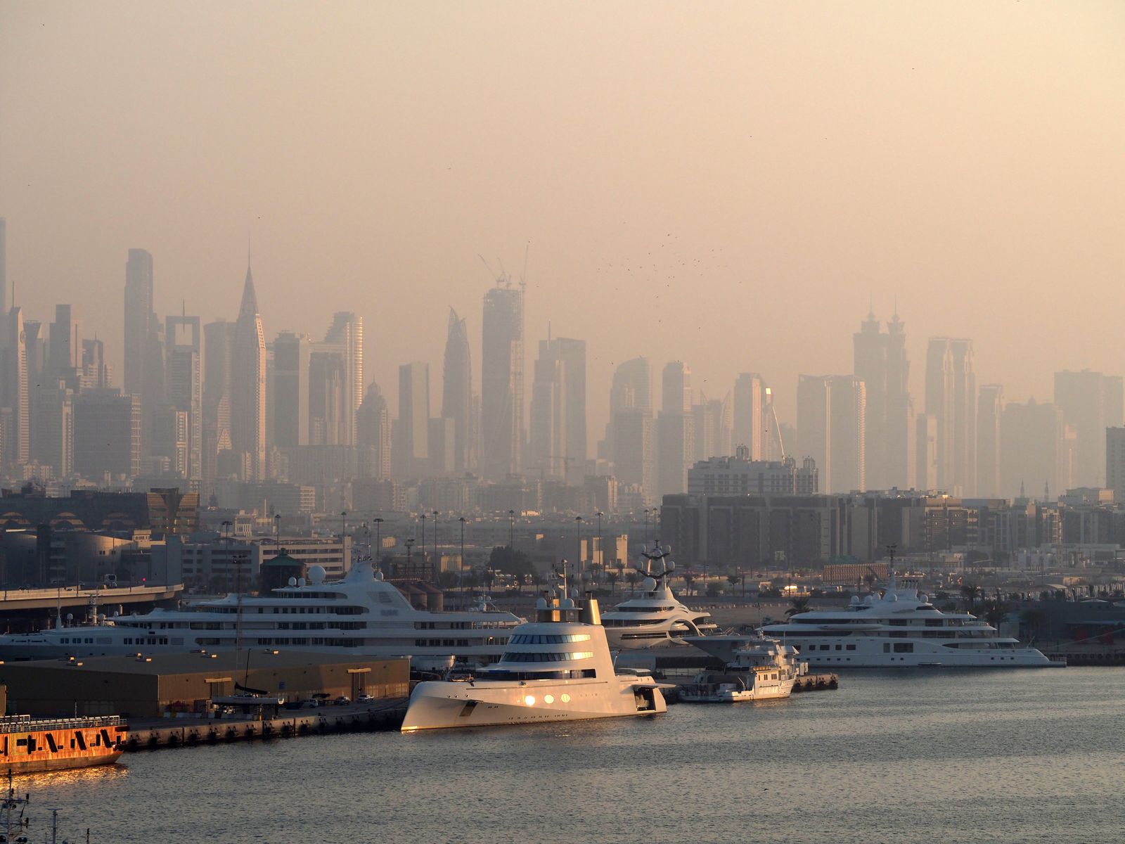 Dubai Marina with luxury yachts against a skyline of iconic skyscrapers in the morning light.